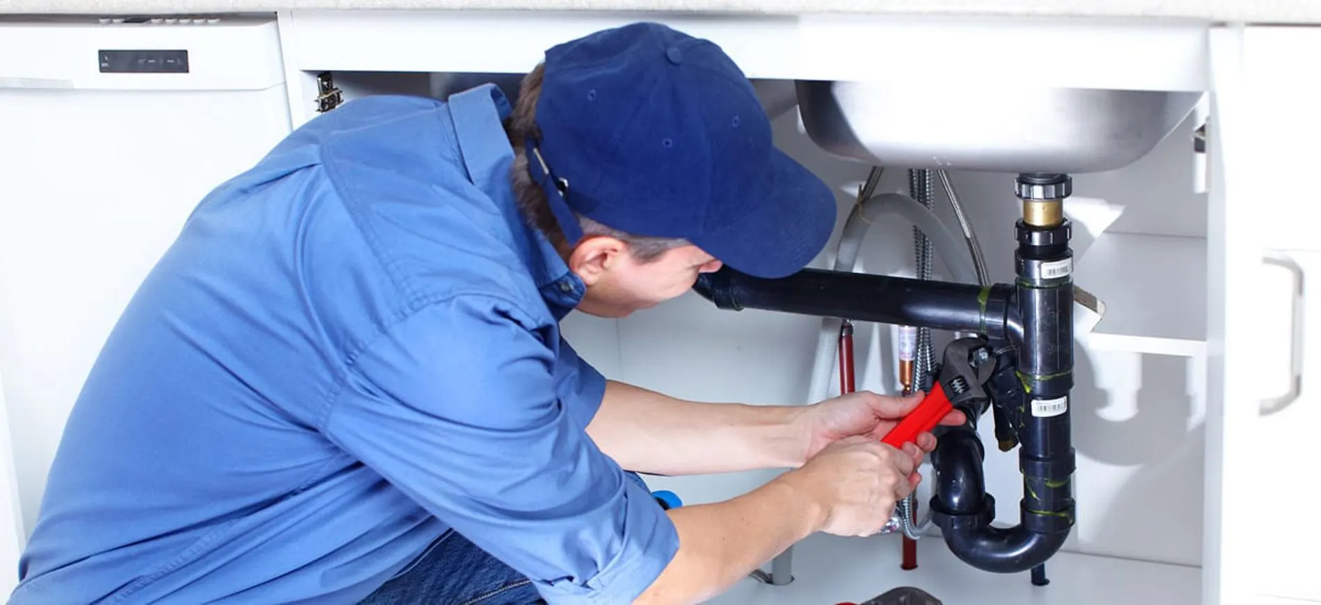 H2O Plumbing technician working under a sink with a wrench on an emergency call