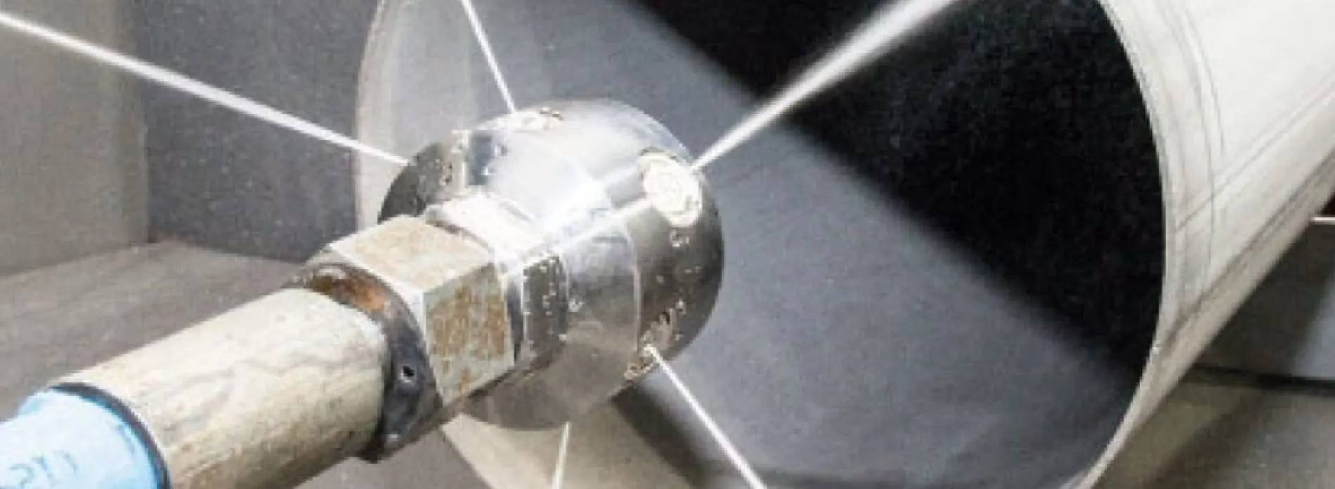 High-pressure hydro jetting nozzle spraying water to scour the inside of a drain pipe